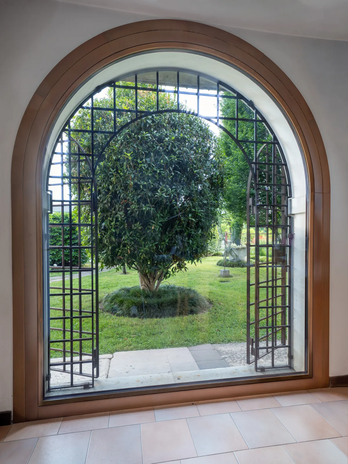 Dall’interno: l’arco in abete tinta noce con vetrata unica sul giardino